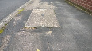 Pavement needs to be patched up around a raised utility cover on Spey Bank